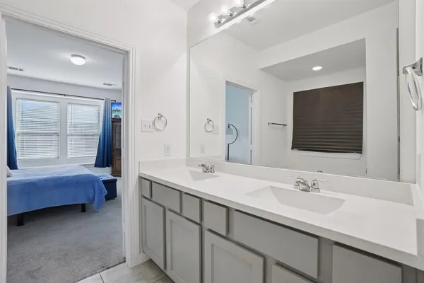 a en suite bathroom with a double vanity sink a large mirror and a bathtub