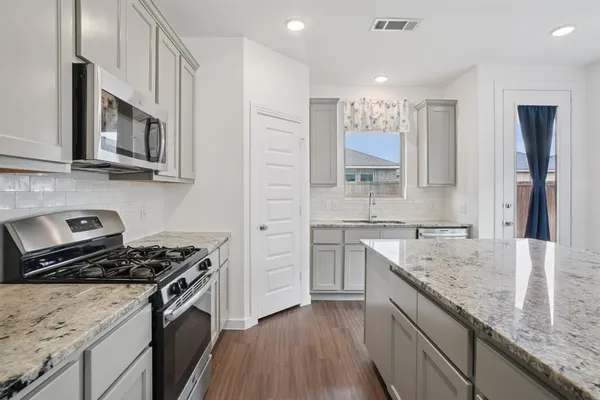 a kitchen with stainless steel appliances granite countertop a sink stove microwave and cabinets
