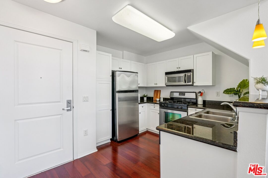 100 South Alameda Street, Unit 477 Los Angeles, CA 90012 - Photo 7 of 24 a kitchen with a refrigerator a stove a sink a counter space and cabinets