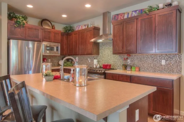 a kitchen with stainless steel appliances granite countertop a table chairs and refrigerator