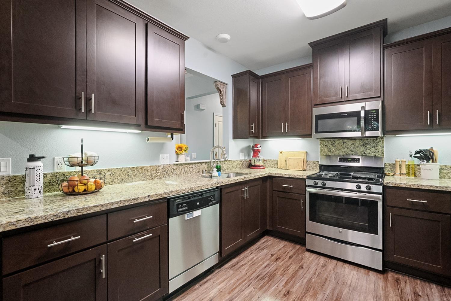 140 Ivy Avenue, Unit A5 Patterson, CA 95363 - Photo 7 of 26 a kitchen with granite countertop stainless steel appliances and wooden cabinets