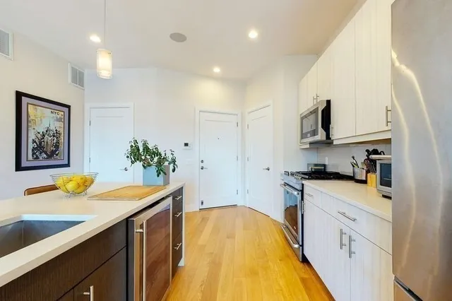 a kitchen with stainless steel appliances a sink a stove a refrigerator cabinets and a window