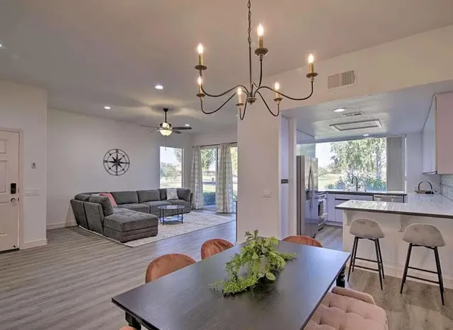 a living room with furniture kitchen area and a chandelier