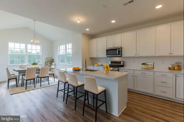 a kitchen with cabinets wooden floor dining table and stainless steel appliances