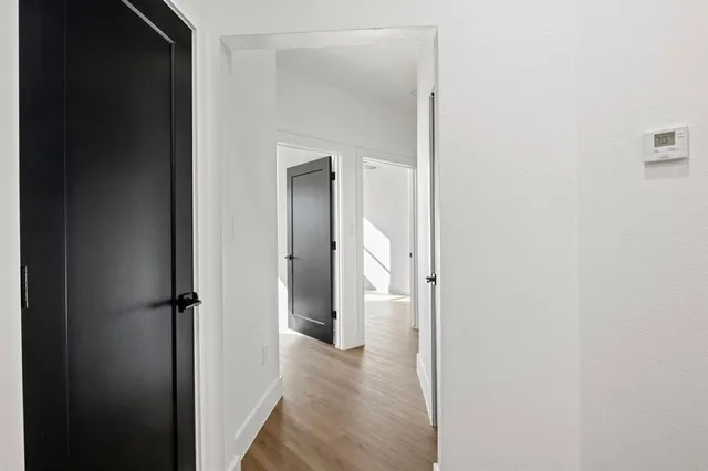 an empty room with wooden floor chandelier fan and windows