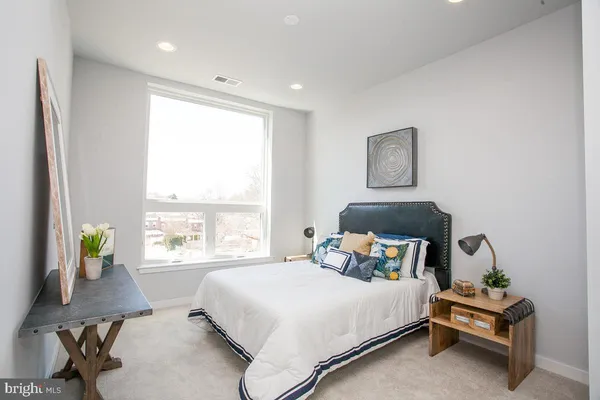 a bedroom with a bed a window and potted plant