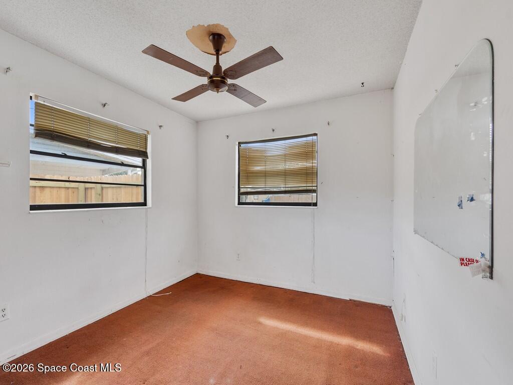 1076 Madrid Road Rockledge, FL 32955 - Photo 17 of 30 a view of a big room with wooden floor ceiling fan and windows