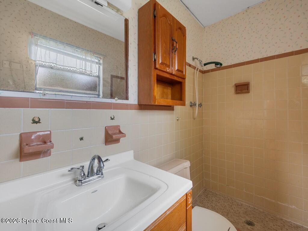 1076 Madrid Road Rockledge, FL 32955 - Photo 5 of 30 a bathroom with a sink a toilet and mirror