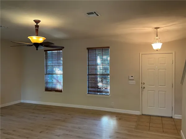 an empty room with wooden floor chandelier and window