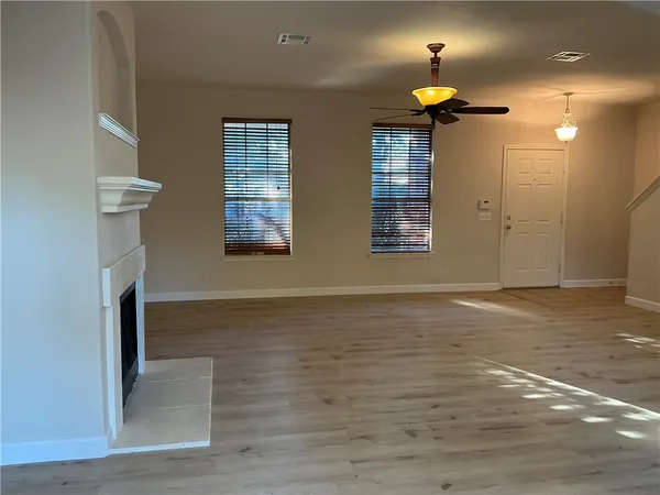 a view of an empty room with window and wooden floor