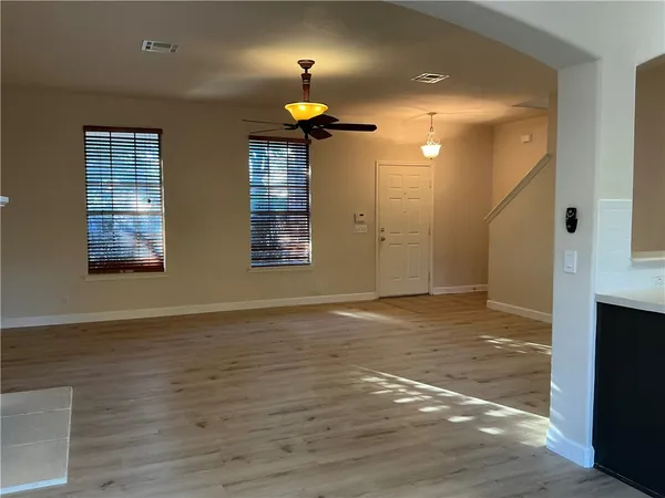 a view of an empty room with window and wooden floor