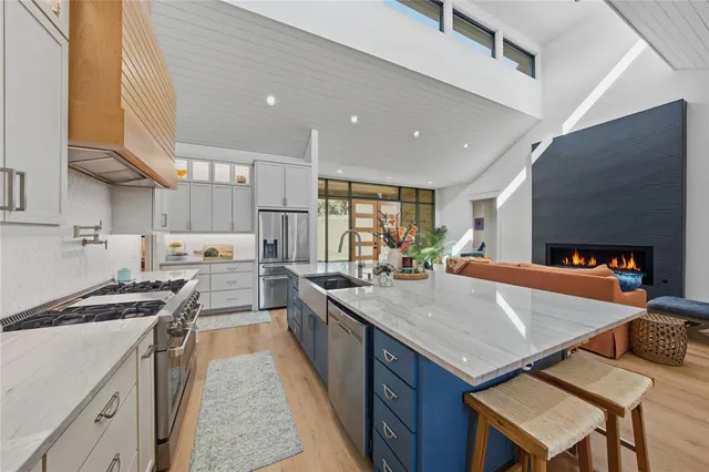 a kitchen with stainless steel appliances granite countertop a stove a sink dishwasher and a refrigerator with wooden floor