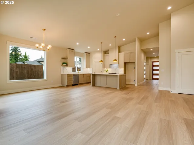 a view of a kitchen with kitchen island a sink wooden floor and a refrigerator