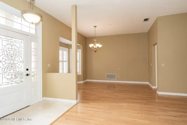 a view of an empty room with window and wooden floor