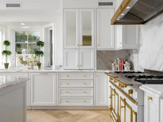 a kitchen with granite countertop a stove a sink and a white cabinets