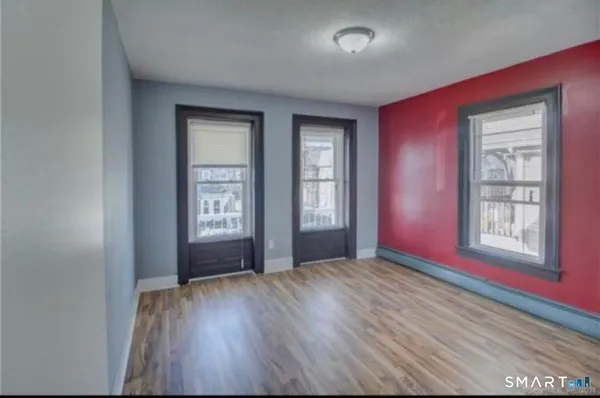 an empty room with wooden floor and windows