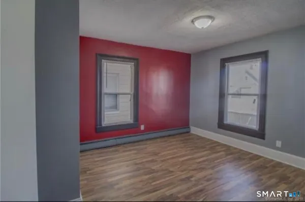 a view of an empty room with wooden floor and closet