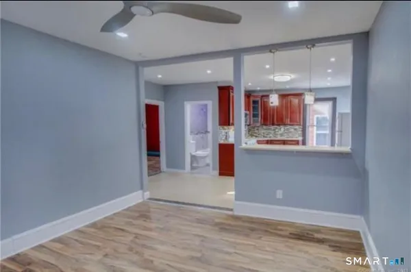 an empty room with wooden floor and a ceiling fan