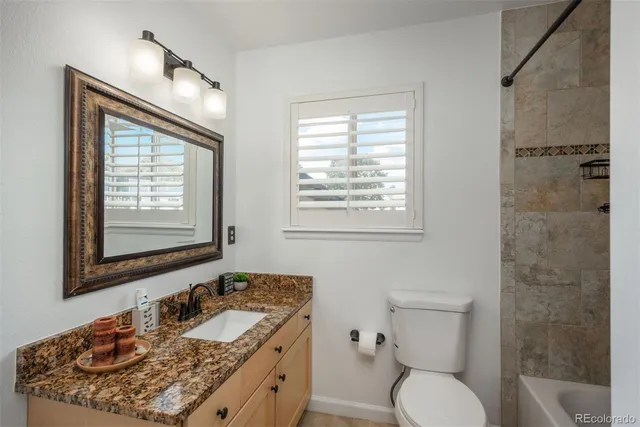 a bathroom with a granite countertop toilet a sink and a mirror