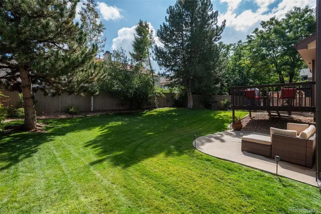 a view of a backyard with couches plants and large trees
