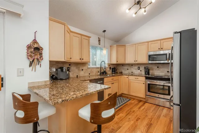 a kitchen with granite countertop kitchen island stainless steel appliances a stove a sink a microwave a refrigerator and cabinets