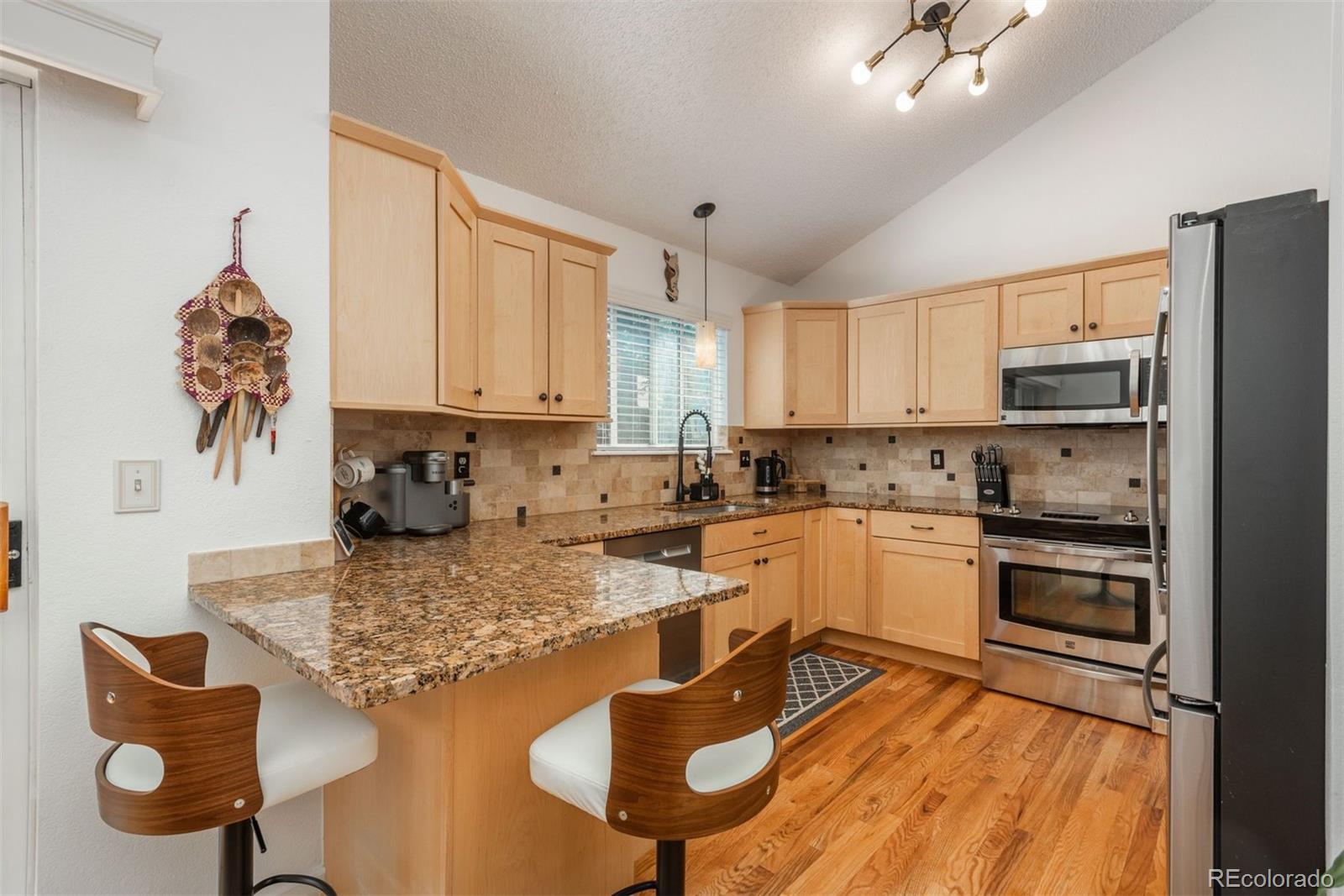 9222 Buttonhill Court Highlands Ranch, CO 80130 - Photo 10 of 44 a kitchen with granite countertop kitchen island stainless steel appliances a stove a sink a microwave a refrigerator and cabinets