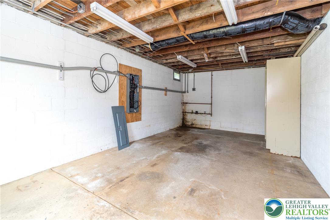 1815 Leithsville Road Hellertown, PA 18055 - Photo 24 of 38 A utilitarian space featuring exposed wooden joists, bright fluorescent lighting, and a concrete floor.
