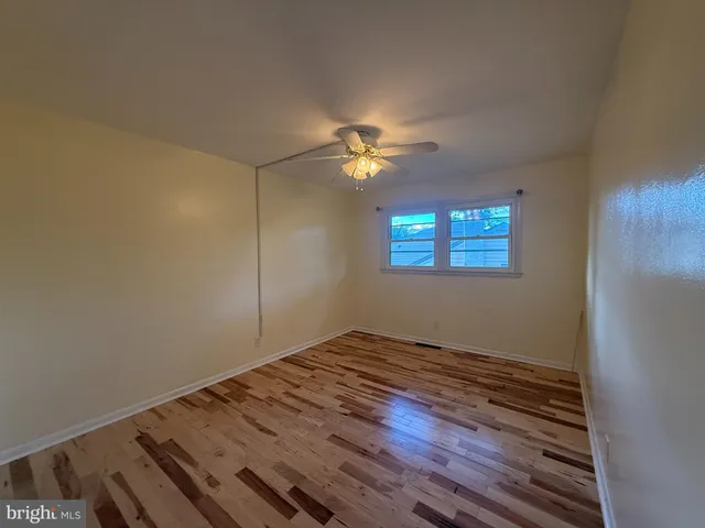 a view of an empty room with window and chandelier fan