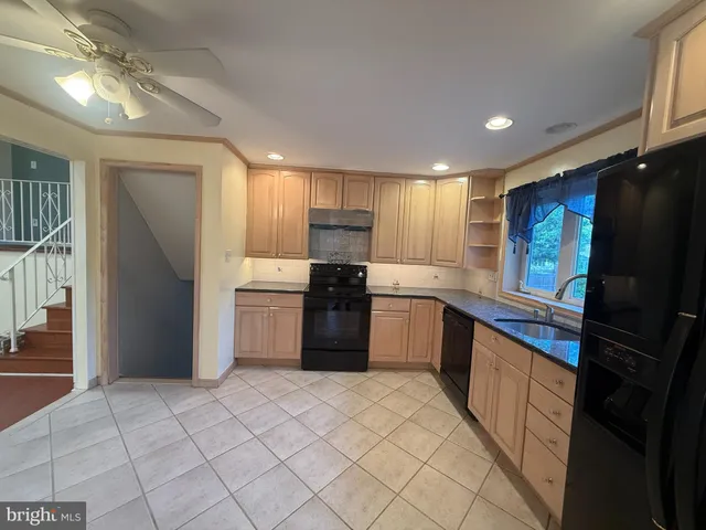 a large kitchen with a stove top oven a sink and dishwasher a refrigerator with wooden floor