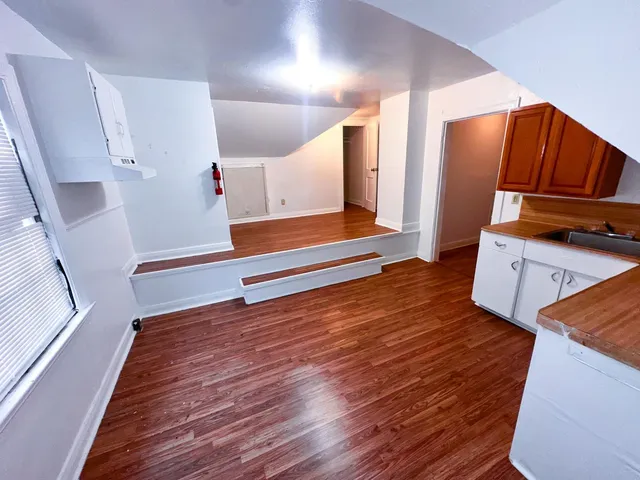 a view of an empty room with wooden floor and stairs