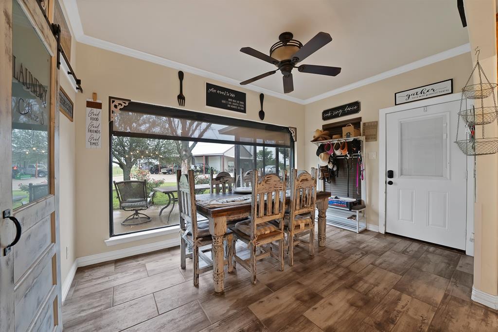 100 Shadle Ridge Court Poolville, TX 76487 - Photo 14 of 40 Dining area featuring wood-finish flooring, a ceiling fan, crown molding, a large picture window, and a barn door with a glass insert