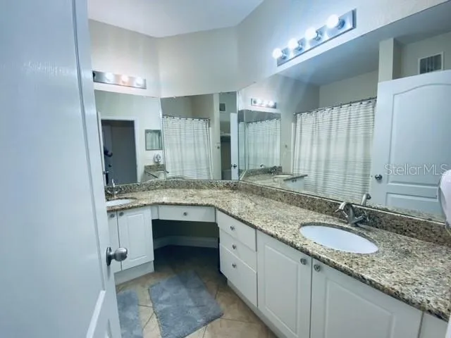 a bathroom with a granite countertop double sink and a mirror