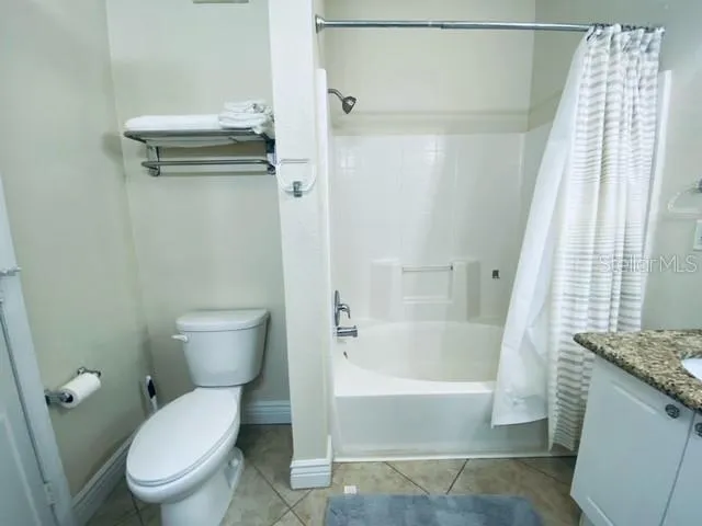 a bathroom with a granite countertop toilet and a bathtub