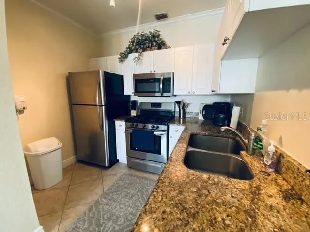a kitchen with stainless steel appliances granite countertop a refrigerator a stove top oven a sink and dishwasher