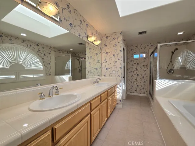 a spacious bathroom with a sink a shower and a mirror