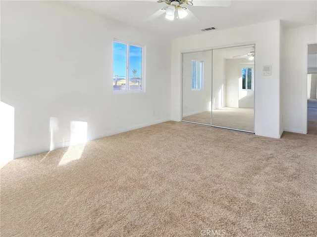 a view of a big room with windows and chandelier fan