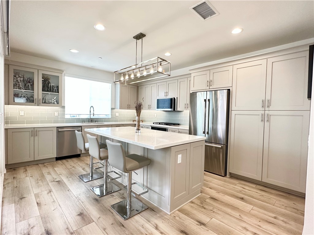 35 Hideaway Loop Mission Viejo, CA 92692 - Photo 3 of 24 a kitchen with stainless steel appliances a sink a stove a refrigerator cabinets and wooden floor