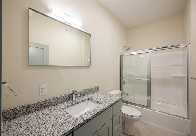 a bathroom with a granite countertop sink toilet and shower