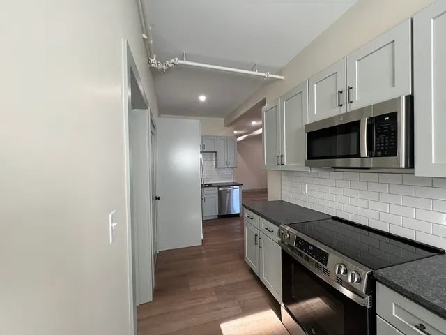 a kitchen with stainless steel appliances and wooden floor