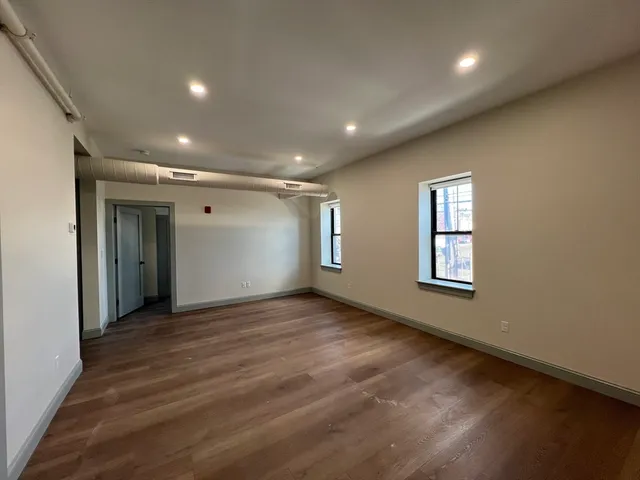 an empty room with wooden floor and windows