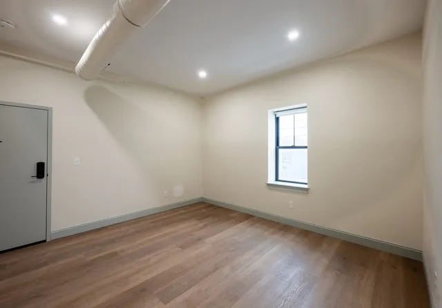 an empty room with wooden floor and windows