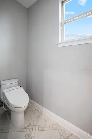 a front view of a house with swing plants and a large tree