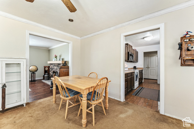 8843 Capernaum Road West Jordan, UT 84088 - Photo 10 of 31 Dining space with crown molding, light colored carpet, a stone fireplace, and a ceiling fan