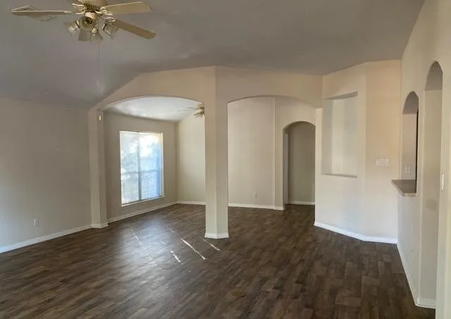an empty room with wooden floor closet and windows