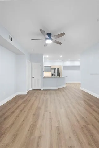 a view of empty room with wooden floor and fan