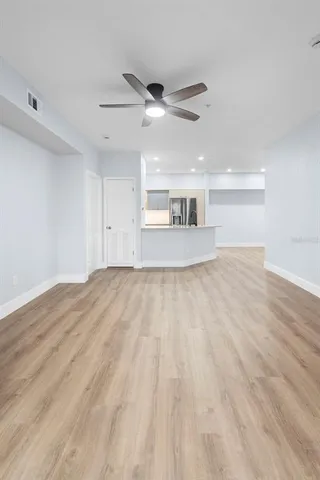 a view of empty room with wooden floor and fan