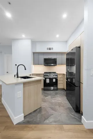 a kitchen with stainless steel appliances granite countertop a stove a sink and a refrigerator