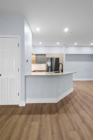 a view of kitchen with stainless steel appliances granite countertop a stove and a wooden floors