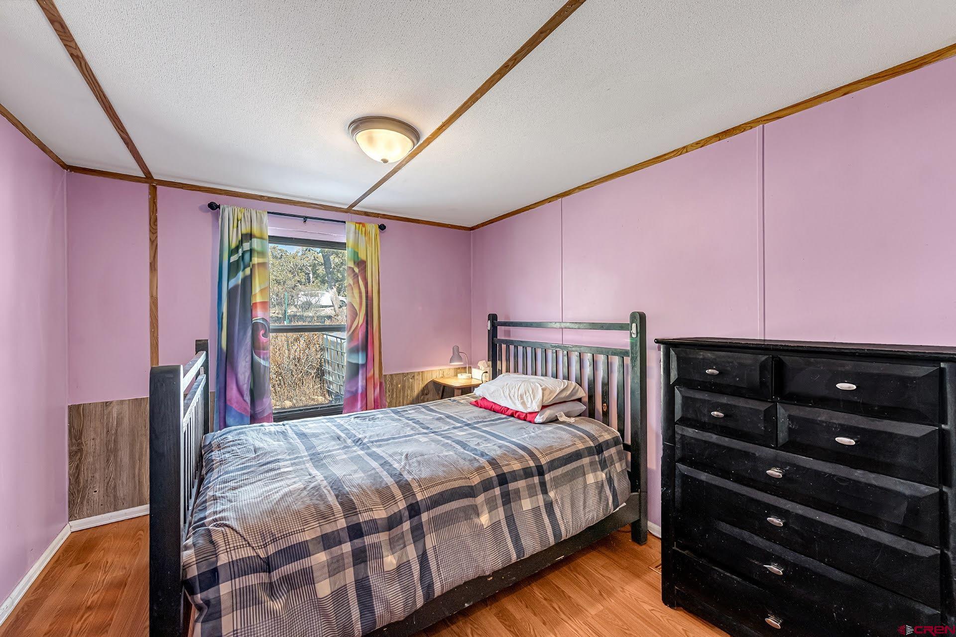 20984 Upland Road Cedaredge, CO 81413 - Photo 28 of 34 a bedroom with a bed a chandelier and large window