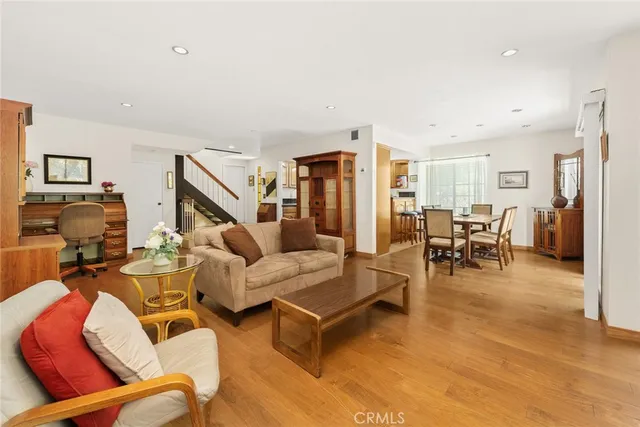 a living room with furniture and a dining table with wooden floor